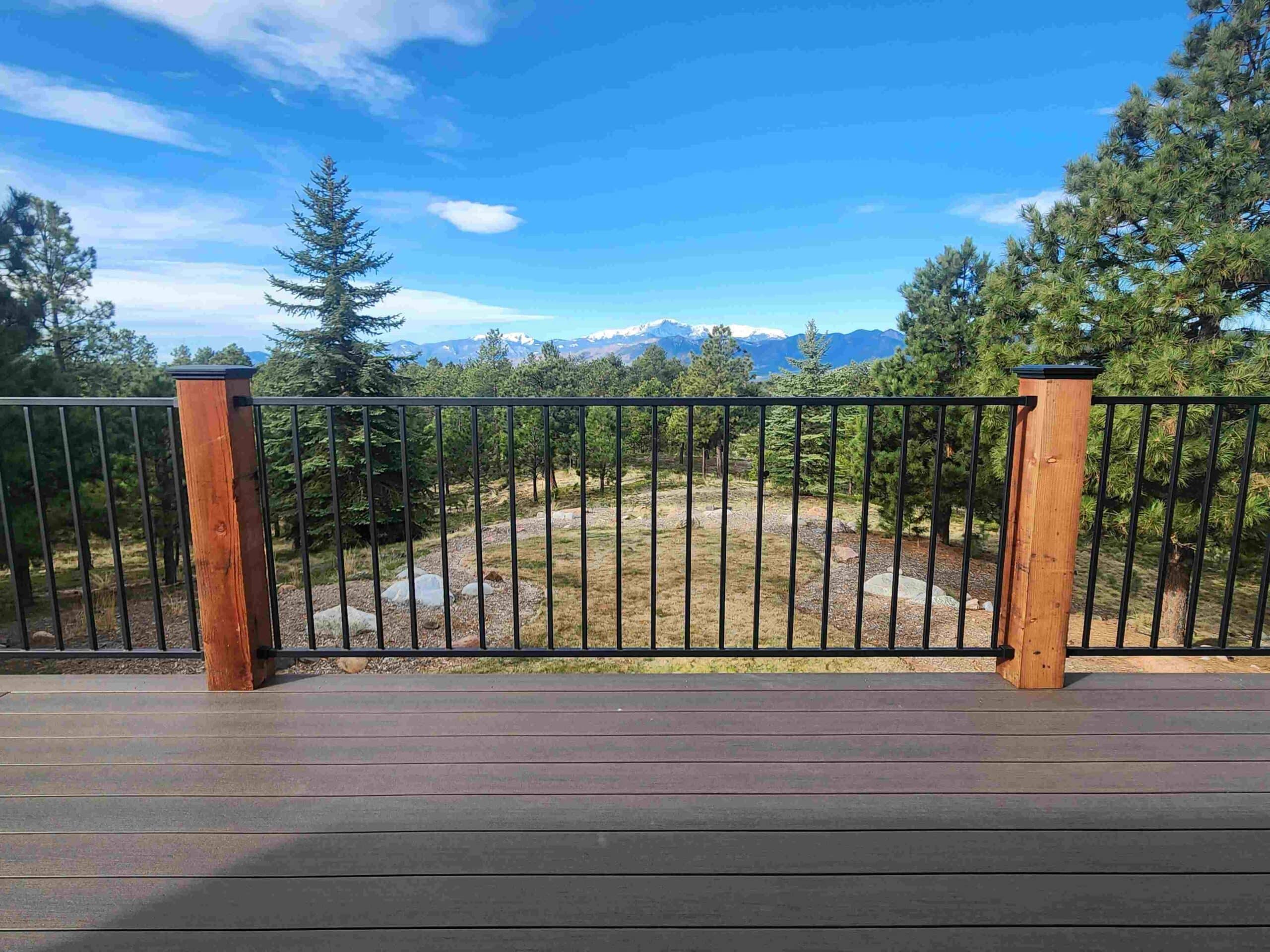 photo of an elevated composite deck overlooking the mountains with black metal railing and wooden deck posts - Composite Decks Builder in Colorado