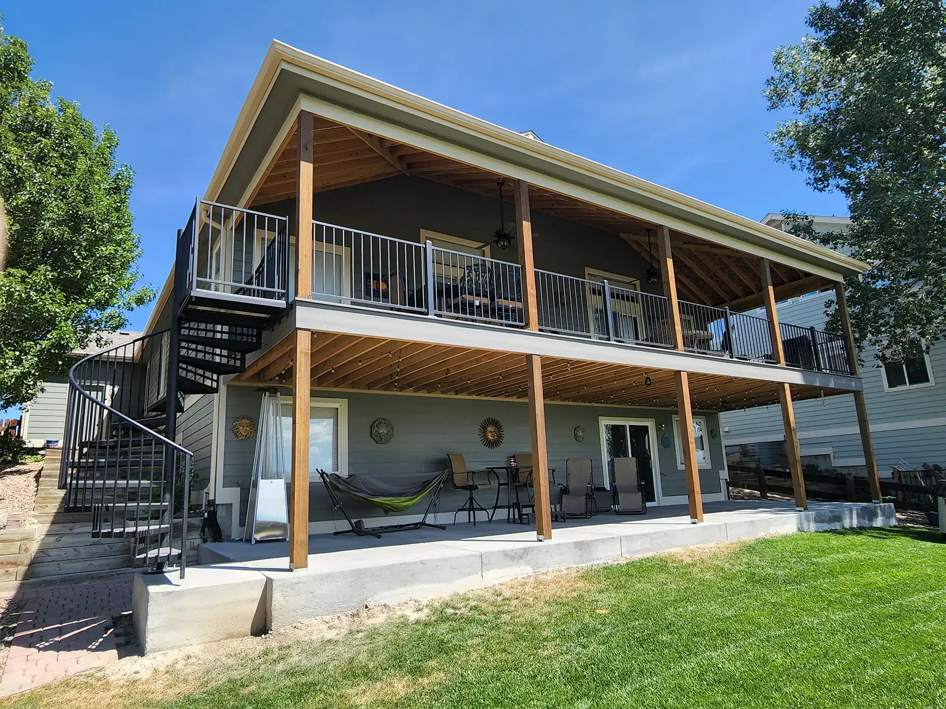 photo of an elevated deck with patio below, spiral staircase, and black metal railing