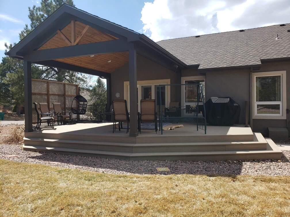 Custom backyard deck with a gabled covered pergola, outdoor seating, and a built-in grilling area.