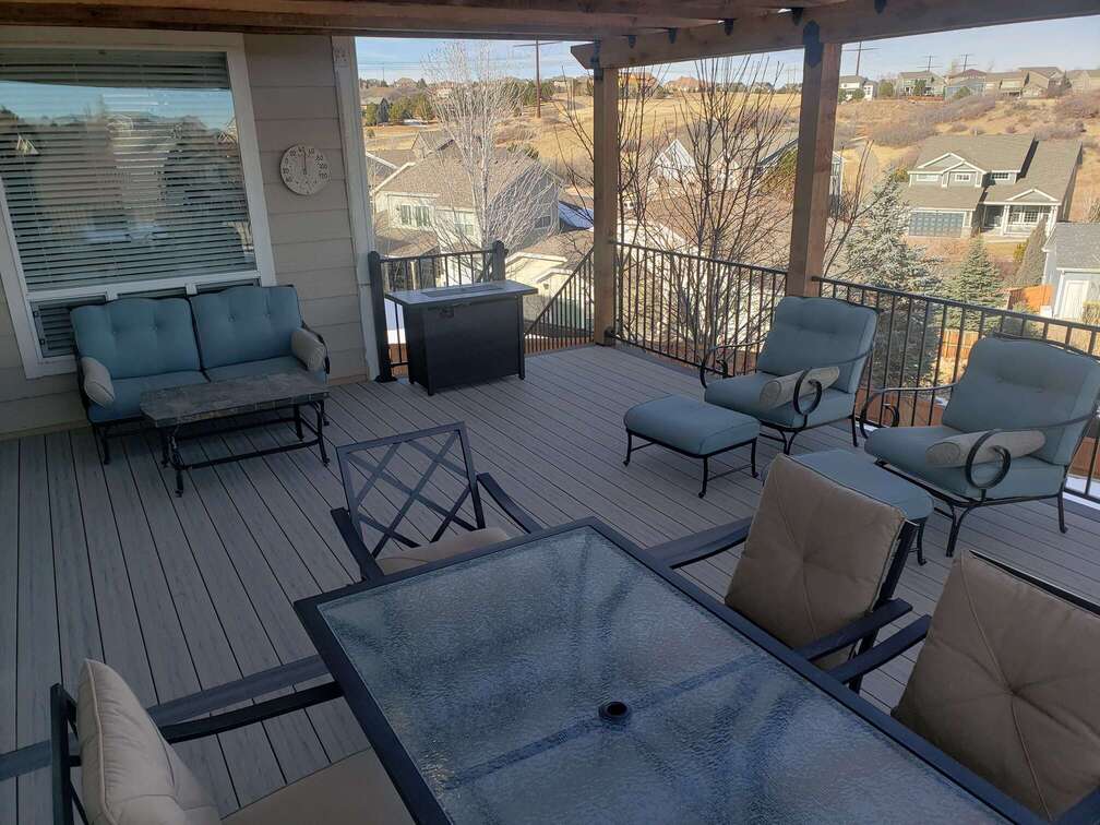 A covered composite deck with outdoor furniture and a scenic suburban view