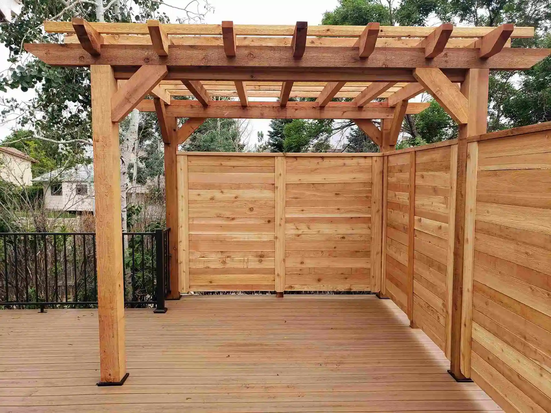 photo of a wooden deck with a wooden privacy screen and wooden pergola - Composite Decking Vs Wood Decks