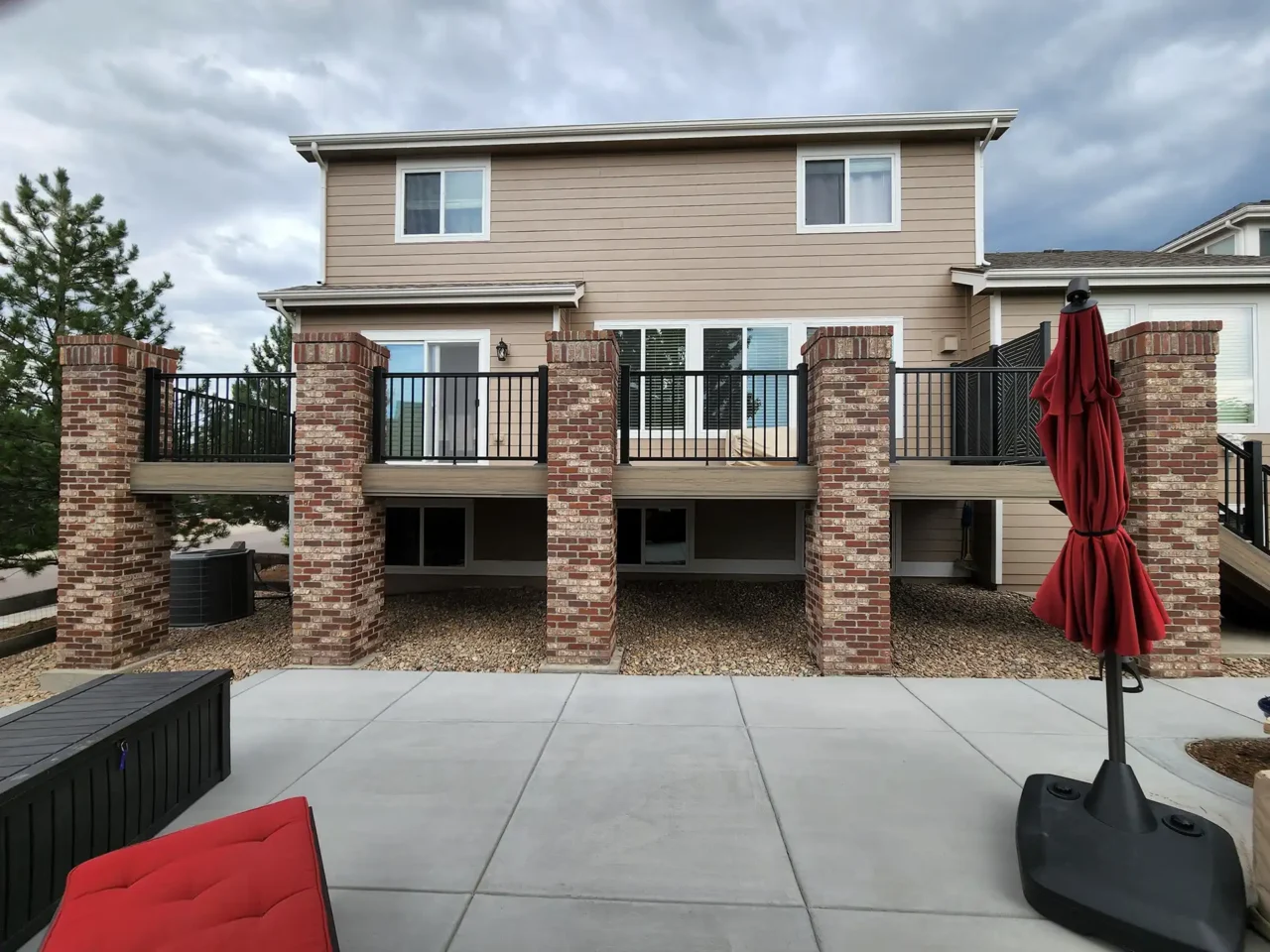 photo of a raised deck with deck railing and brick columns and concrete patio - Deck building process