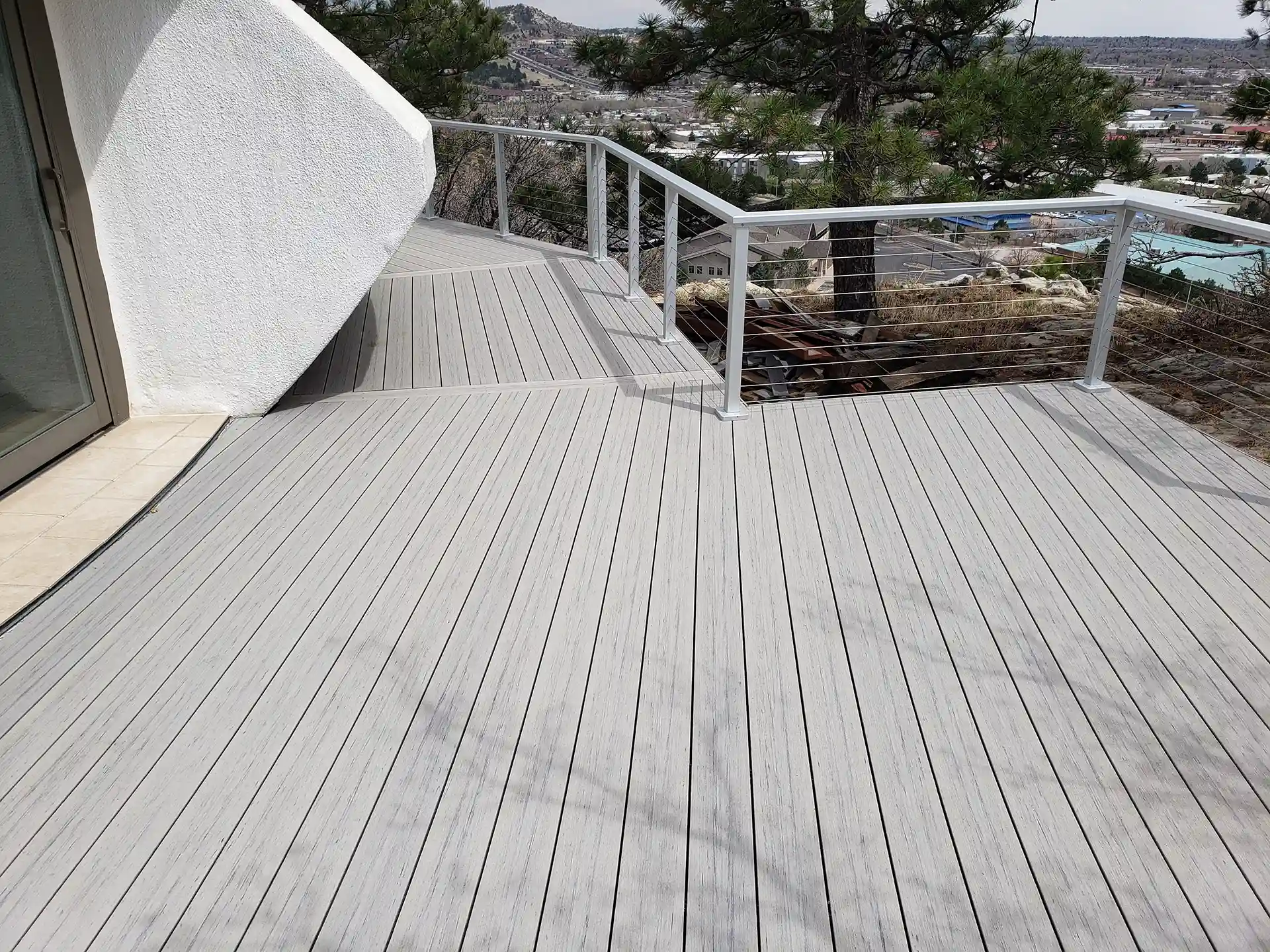 Light gray Trex deck with clean lines and modern cable railing, overlooking a scenic view