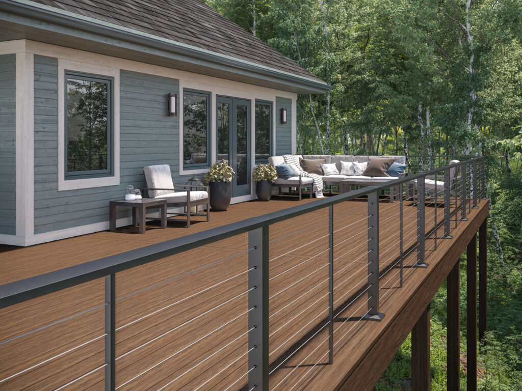 Spacious elevated wood deck with modern cable railing, outdoor seating, and forest views attached to a home