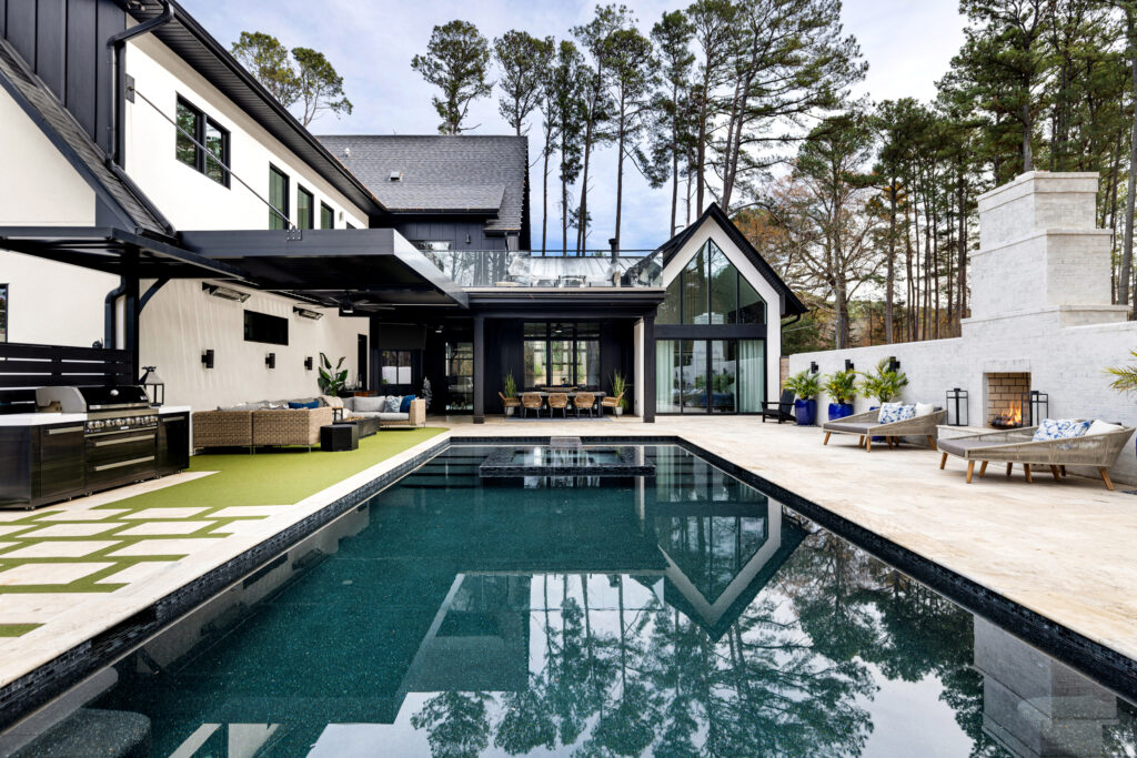 Luxury backyard with motorized louvered pergola, poolside lounge seating, fire pit table, and outdoor kitchen grill area