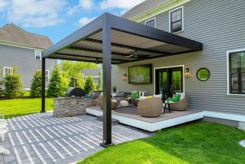 Modern attached Azenco R-Blade aluminum pergola covering a luxury outdoor kitchen and lounge area at a Colorado home, creating a functional outdoor living space with shade and weather protection.
