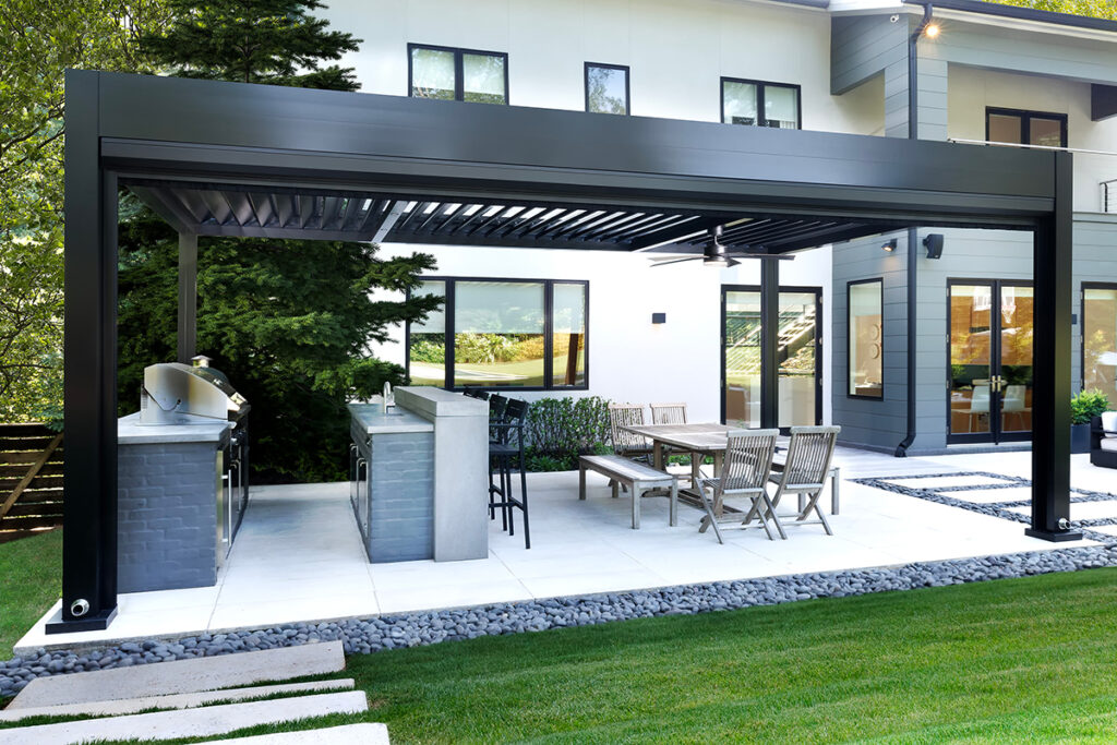Modern aluminum louvered pergola covering an outdoor kitchen and dining patio at a luxury contemporary home with landscaped backyard.