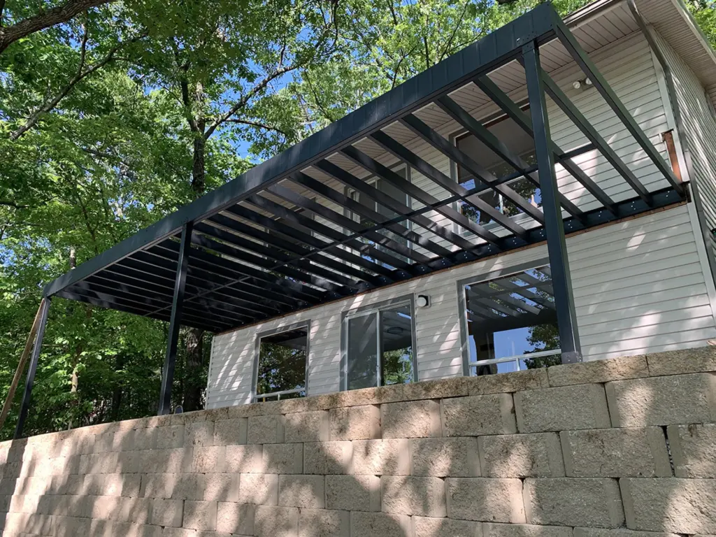 black-steel-deck-framing-attached-on-the-residential-house-with-sliding-glass-door-and-multiple-windows-with-big-trees-on-the-back-in-castle-rock-co