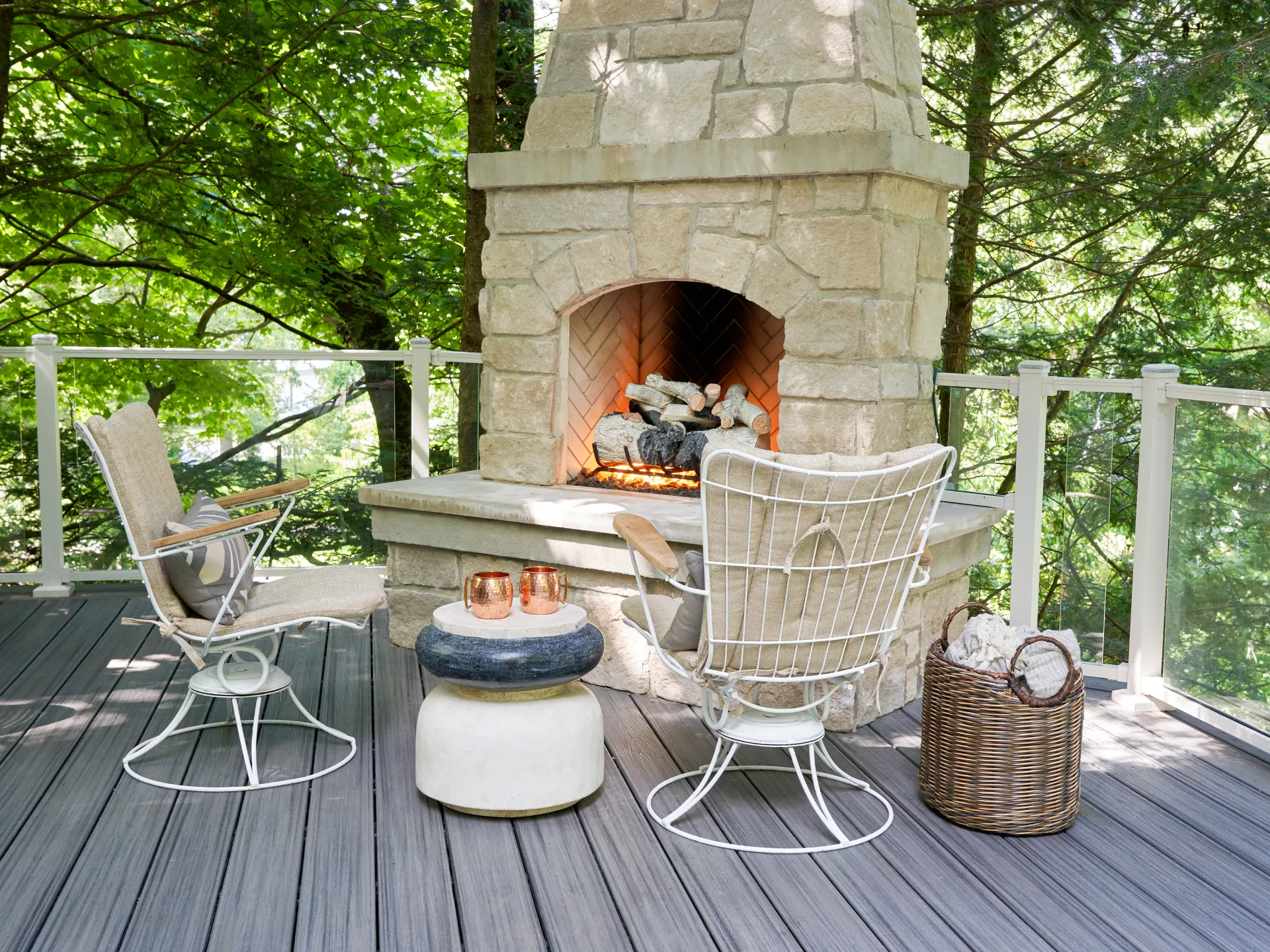 composite-deck-with-glass-railings-and-outdoor-chairs-and-small-table-on-the-fire-place-on-the-wall-with-trees-on-the-background-in-castle-rock-co