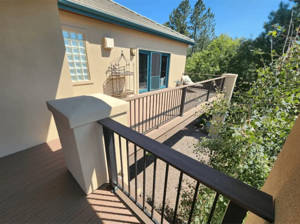deck-on-the-side-of-the-house-with-black-railings-and-blue-trim-door-on-the-mocha-house-with-trees-in-the-background-in-castle-rock-co