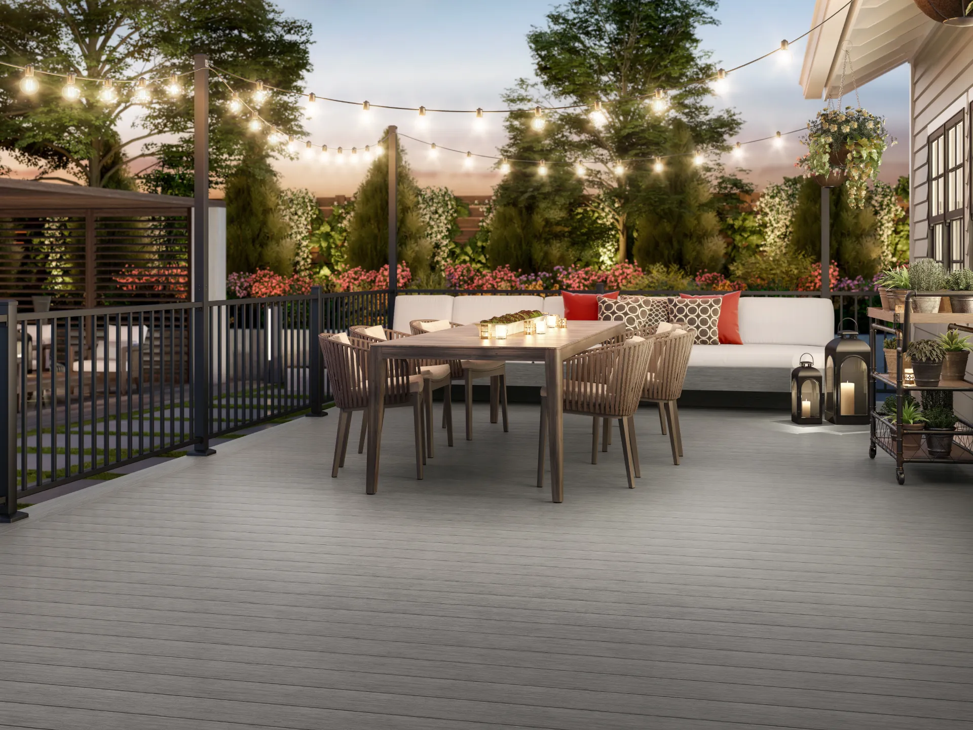 gray-composite-deck-with-black-metal-railings-and-luxury-outdoor-living-dining-set-with-couch-and-decorative-potted-plants-surrounded-by-beautiful-plants-and-grass-in-castle-rock-co