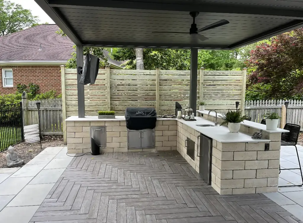 outdoor-living-kitchen-with-potted-plants-and-a-fan-on-the-ceiling-of-louvered-pergola-featuring-picket-privacy-fence-in-castle-rock-co