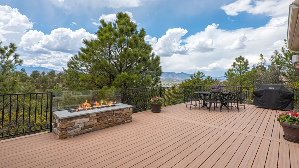 residential-deck-installation-with-outdoor-living-dining-area-with-potted-plants-and-firepit-with-black-metal-railings-featuring-trees-cloudy-sky-and-city-view-in-castle-rock-co