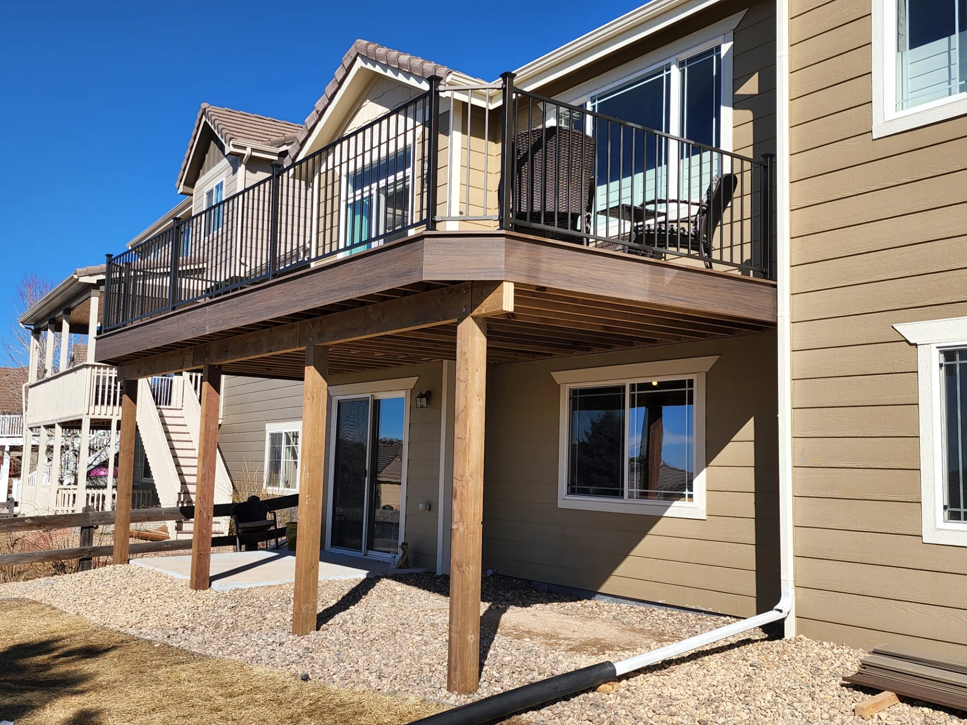 under-deck-framing-with-black-metal-railings-and-outdoor-living-space-featuring-a-porch-on-the-side-of-the-beige-house-in-castle-rock-co